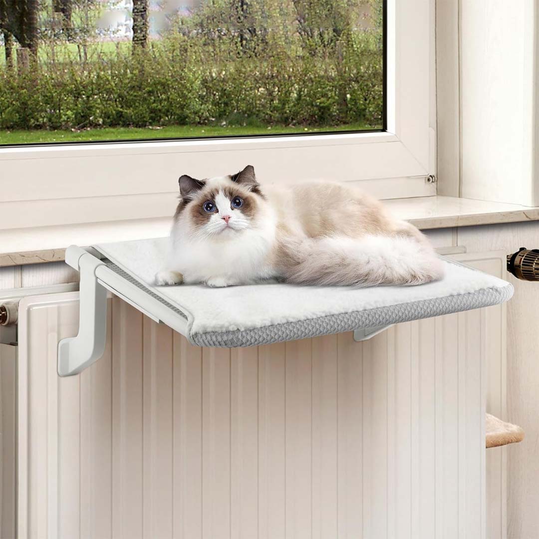 Un chat se repose sur un perchoir suspendu à un radiateur